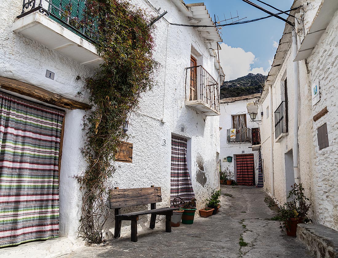 Calle típica de Bubión en la Alpujarra, donde las puertas están cubiertas con alfombras de lana.